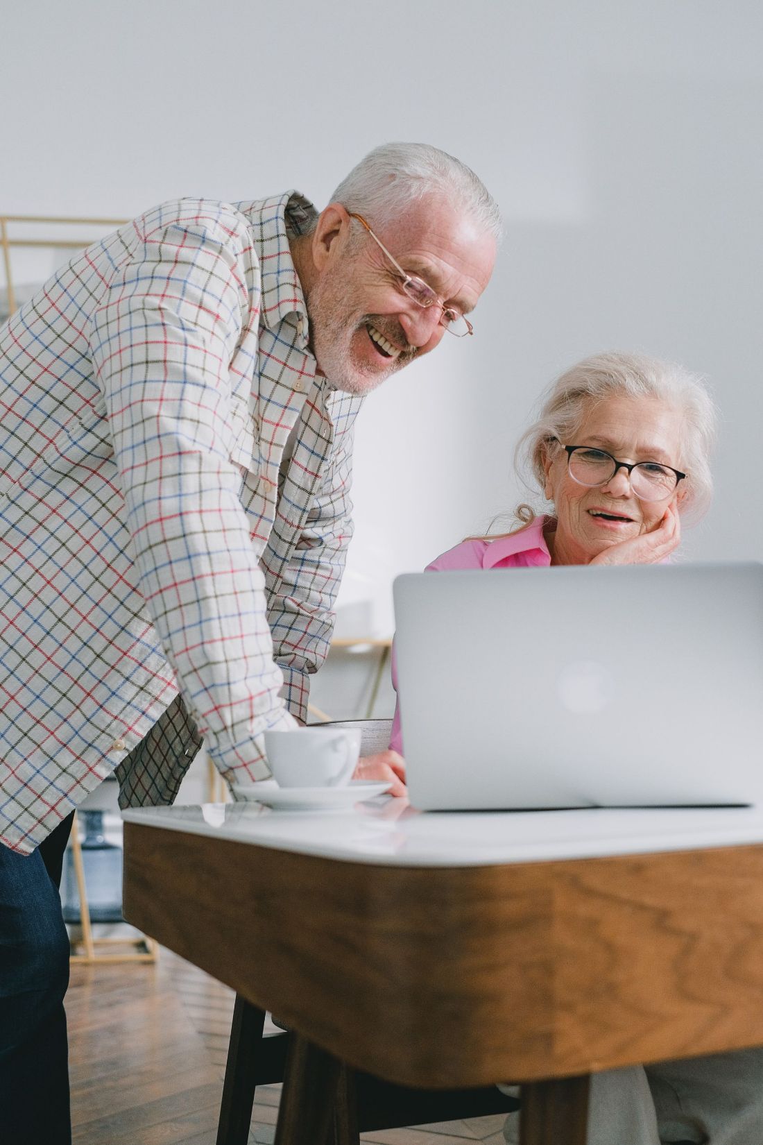 An older couple laughing together at their laptop
