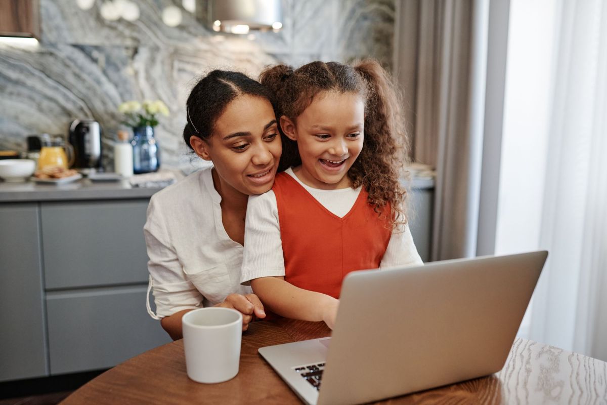 A mom and her daughter laughing at a laptop